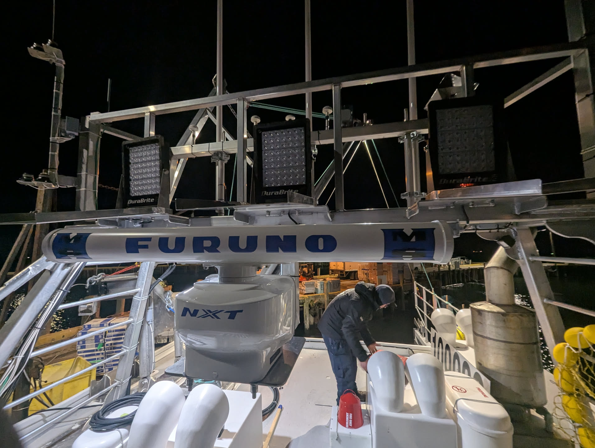 Hines Marine technician installing a Furuno NXT radar on a fishing vessel at night